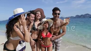 人们在海滩上的手机上自拍，在度假时微笑的年轻游客团体